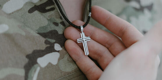 Ein christiliches Silberkreuz am Halse eines Mannes, der eine Soldatenuniform trägt.