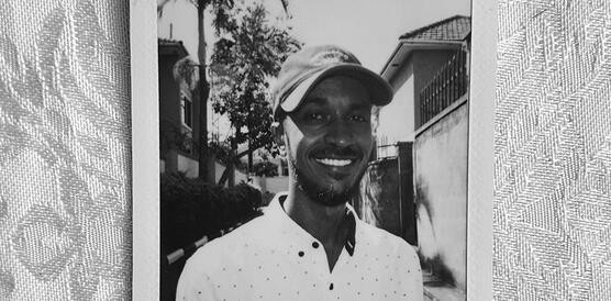 Ein junger sudanesischer Mann mit Hemd und Baseballmütze.