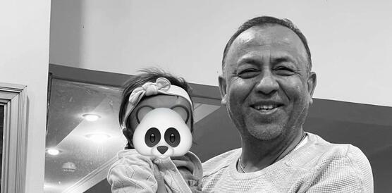 Das Foto zeigt Sylvain Rabetsaroana, der ein kleines Kind auf dem Arm trägt. Er lächelt in die Kamera. Das Foto wurde digital bearbeitet, um das Gesicht des Kindes unkenntlich zu machen. Auf dem Gesicht wurde ein Panda-Gesicht digital platziert.
