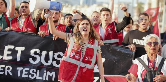 Demonstrationszug mit einer Frau an der Spitze, die ein Megafon hoch hält