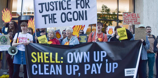 Demonstration mit Protestschildern und Shell-Zeichen