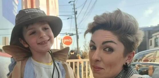 Das Foto zeigt Lera Burlakova, die in der Hocke ein Selfie macht zusammen mit ihrem Sohn, der lachelnd links neben ihr steht.