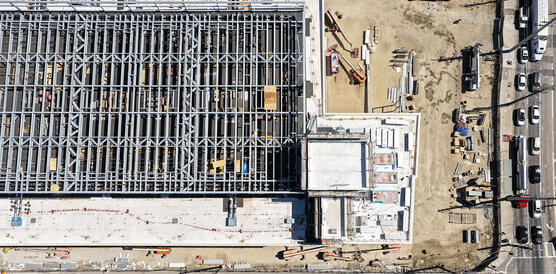 Vogelperspektive auf eine Baustelle, auf der ein Rechenzetrum entsteht: Stahlträger, Mauern, drumherum Autos und LKW.