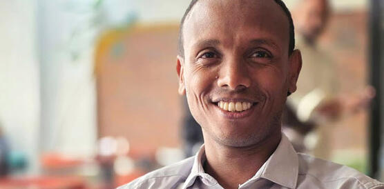 Ein Mann sitzt mit verschränkten Armen draußen und lächelt, es ist der Menschenrechtsverteidiger und Autor Befekadu Hailu.