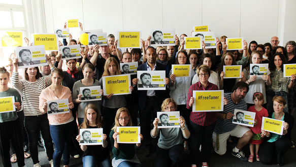 Amnesty-Mitarbeiterinnen und -Mitarbeiter halten Schilder hoch