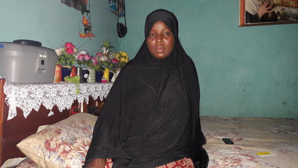 Aissatou Lamarana Diallo sitzt auf dem Bett in einem Zimmer