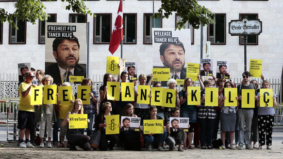 Amnesty Aktivisten halten Schilder für die Freilassung von Taner Kılıç vor der Türkischen Botschaft in Berlin hoch