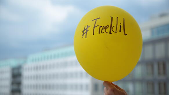 Hand hält gelben Luftbalon mit der Aufschrift #FreeiIdil
