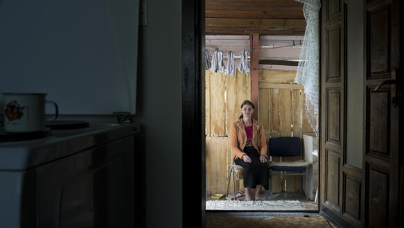 Eine Frau sitzt auf einem Stuhl hinter der geöffneten Haustür