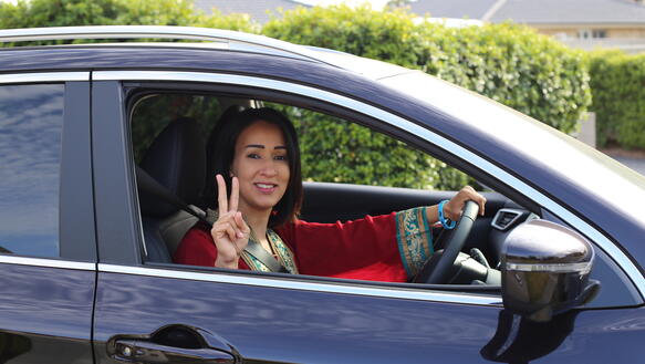Die saudi-arabische Aktivistin Manal al-Sharif sitzt in ihrem Auto in Australien und zeigt mit der Hand das Peace-Zeichen