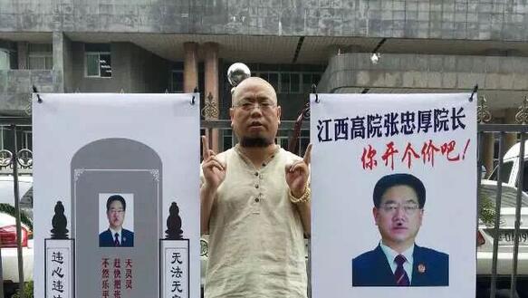 Wu Gan steht zwischen zwei aufstellbaren Bannern. Im Hintergrund graue Häuser