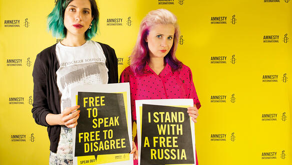 Maria Alyokhina und Nadezhda Tolokonnikova von Pussy Riot halten Plakate von Amnesty International.