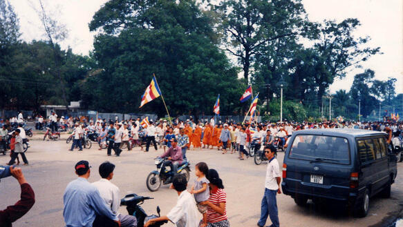 Menschenmenge auf der Straße, es werden Flaggen geschwenkt