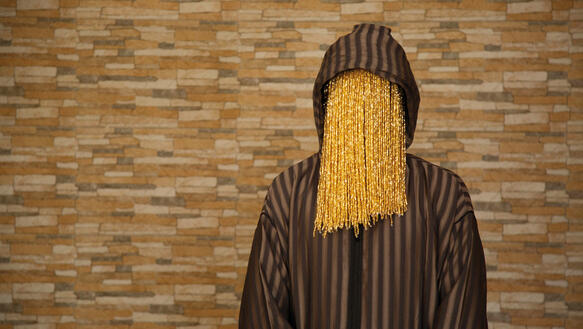 Der Undercover-Journalist Anas Aremeyaw Anas mit einem goldenen Perlenvorhang vor seinem Gesicht.