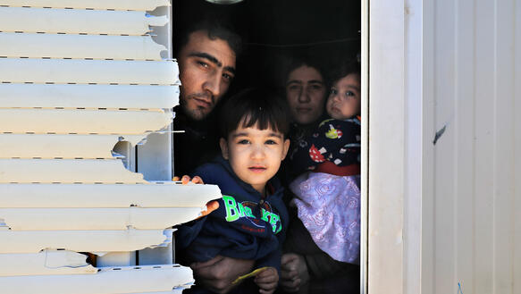 Eine vierköpfige Familie mit ernstem Gesichtsausdruck schaut aus dem Fenster