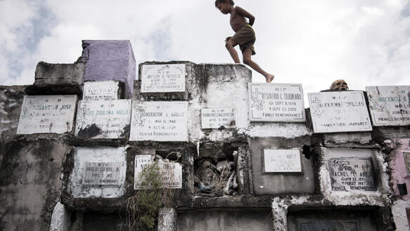 Ein Junge läuft über eine Mauer, auf der Grabinschriften angebracht sind