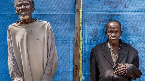 Ein alter Mann und eine alte Frau aus Uganda vor einer blauen Wand