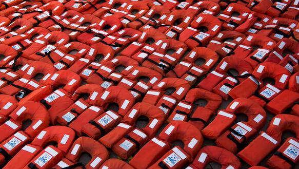 Dutzende rote Rettungswesten, die nebeneinander aufgereiht liegen