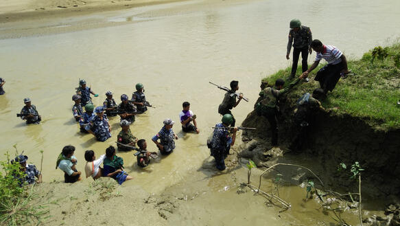 Soldaten helfen Menschen aus einem Fluß auf bergiges Gelände zu steigen