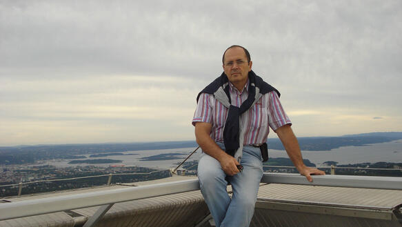 Oyub Titiev sitzt an auf einem Geländer, im Hintergrund eine Flusslandschaft