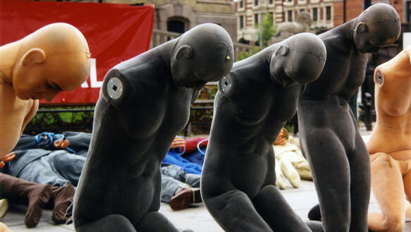 Dummy Puppen sind auf den Knien mit gesenktem Kopf auf einem öffentlichen Platz