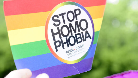 Handfahne in Regenbogenfarben mit Aufschrift Stop Homophobia