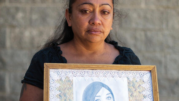 Eine Frau hält mit feuchten Augen die eingerahmte Zeichnung ihrer Tochter in die Kamera