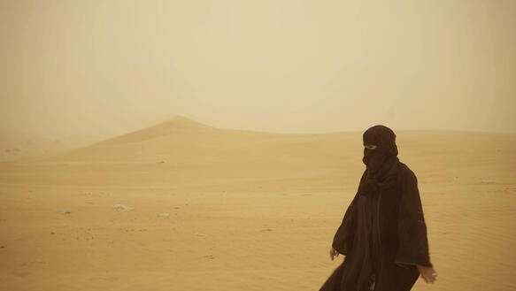 Eine verschleierte Frau geht durch die Wüste