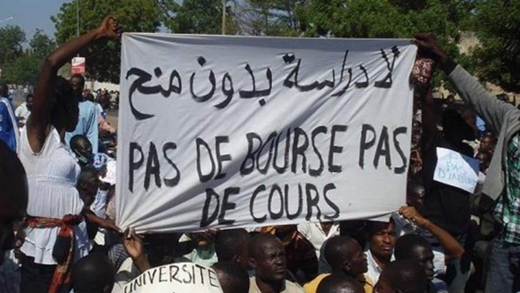 Eine Gruppe von Menschen hält bei einer Demonstration ein Banner hoch, auf dem auf Französisch steht: "Kein Geld, kein Studium"