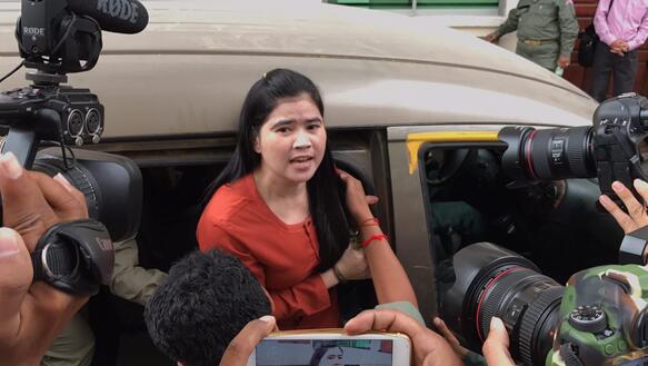 Eine Frau steigt aus dem Auto und wird von mehreren Medienschaffenenden fotografiert