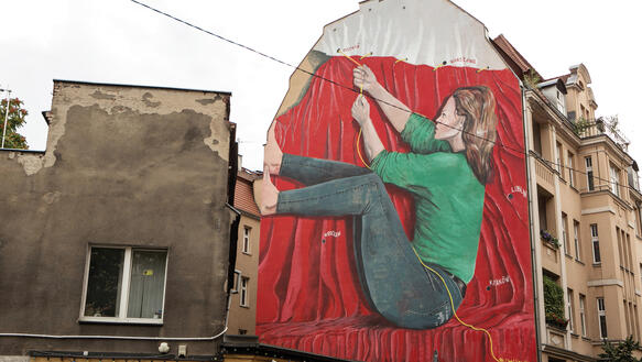 Wandbild einer Frau, die an einer Schnur zieht, die eine polnische Flagge zusammenhält