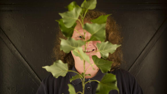 Porträtfoto von Steffi mit einem Blätterzweig vor dem Gesicht