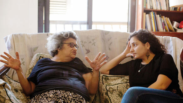 Eine alte Frau und eine junge Frau sitzen auf einem Sofa und unterhalten sich