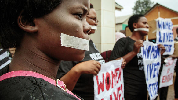 Mehrere Frauen haben sich mit zugeklebtem Mund und Bannern bei einem Protest versammelt