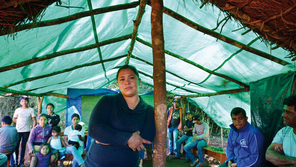 Eine Frau steht in einem Zeltpavillon – umgeben von mehreren anderen Personen