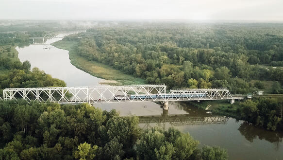 Ein Zug fährt über eine Brücke, die über einen Fluss führt.