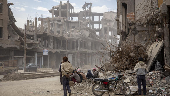 Einige Zivilpersonen zwischen zerstörten Häusern in der syrischen Stadt Rakka