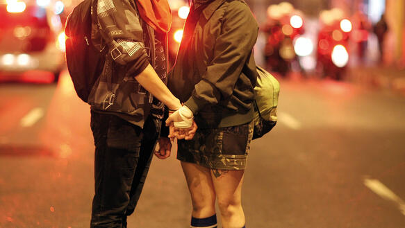 Ein Liebespaar hält sich auf einer Straße die Hände.