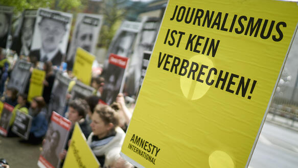 Eine Gruppe von Amnesty Aktivisten steht vor der türkischen Botschaft in Berlin und hält Schilder mit der Aufschrift "Journalismus ist kein Verbrechen" hoch.