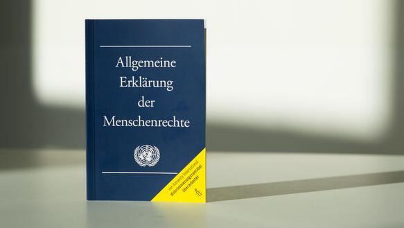 Allgemeine Erklärung der Menschenrechte als Broschüre: weißer Hintergrund mit Schattenwurf.