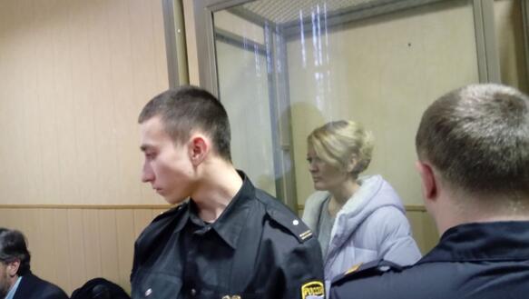Anastasia Shevchenko im Hintergrund bei der Verhandlung in einem Glaskasten zu sehen.