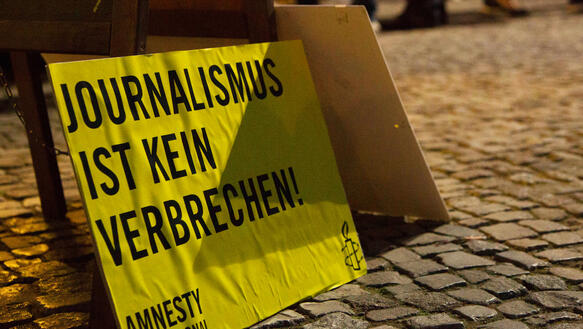 Protestschild mit der Aufschrift "Journalismus ist kein Verbrechen" steht auf dem Boden