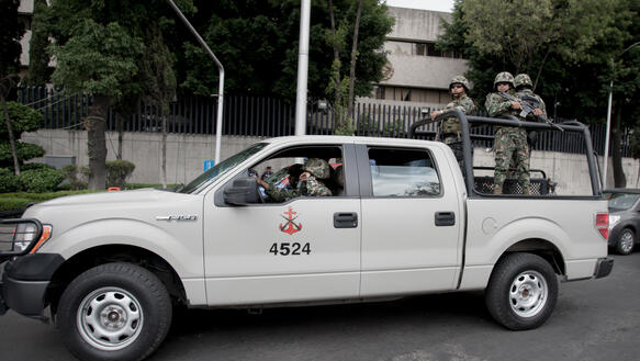 Weißer Pick-Up mit mexikanischen Soldaten in voller Kampfausrüstung und Waffen