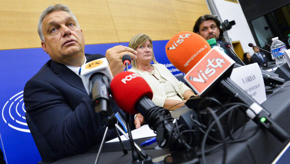 Mehrere Personen sitzen an einem Tisch mit vielen Mikrofonen, Viktor Orban im Vordergrund