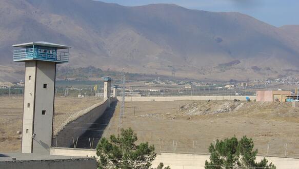 Wachturm und Mauer eines Gefängnisses, im Hintergrund eine sandige Berglandschaft