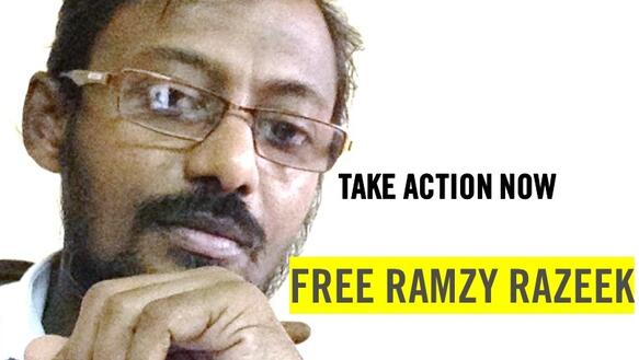 Die Grafik zeigt ein Porträtfoto von Ramzy Razeek. Er trägt eine Brille. Auf der Grafik steht unter anderem: "Free Ramzy Razeek".