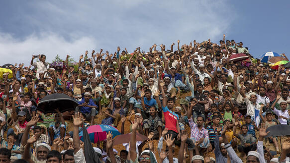Hunderte Menschen stehen dicht an dicht, manche tragen Schirme, um sich vor der Sonne zu schützen