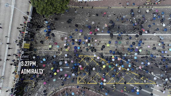 Aufnahme aus der Vogelperspektive: Hunderte Menschen mit Regenschirmen