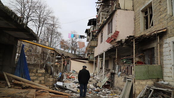 Ein Mann steht vor einem zerstörten Wohngebäude.