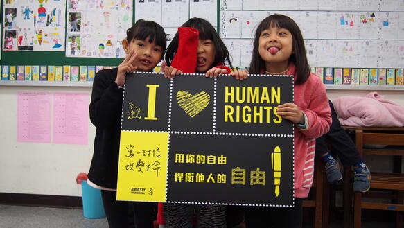 Das Bild zeigt Kinder mit einem Schild in der Hand. "Ich liebe Menschenrechte"